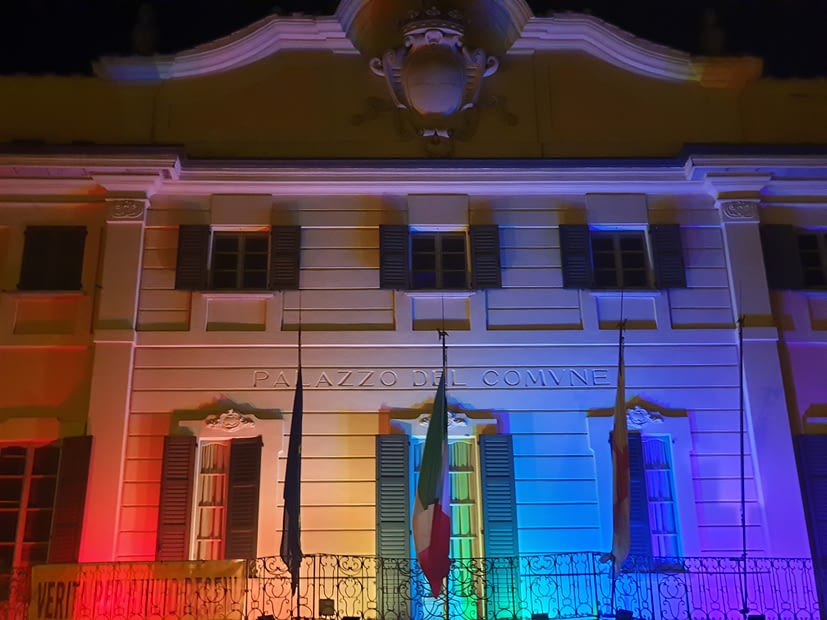 Foto di Palazzo Estense, sede del Comune di Varese, con un fascio di luce proiettato verso l'alto raffigurante i colori della bandiera arcobaleno.